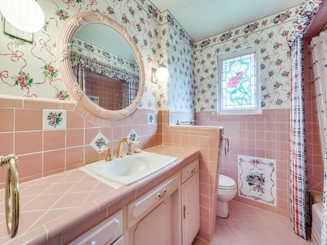6815 E Mockingbird Ln, Dallas, TX 75214 - bathroom with wallpapered walls, vanity, wainscoting, toilet, and tile patterned flooring