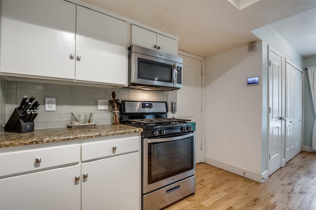 3964 Lost Creek Dr, Dallas, TX 75224 - kitchen featuring stainless steel appliances, light wood-style floors, tasteful backsplash, and white cabinetry