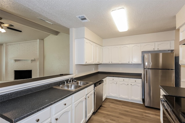1421 Monica Ct, Mesquite, TX 75149 - kitchen featuring appliances with stainless steel finishes, a sink, dark countertops, white cabinets, and a textured ceiling