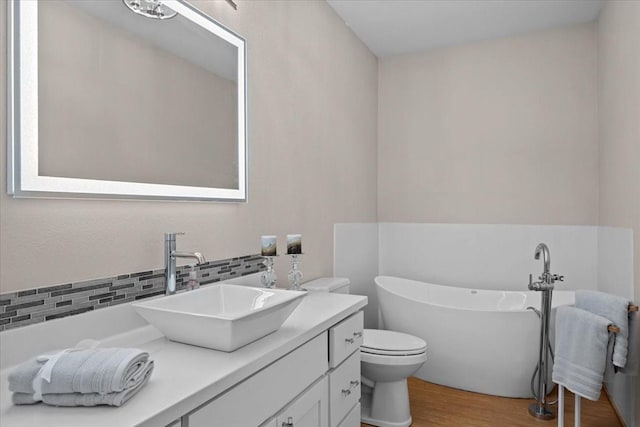 114 Deer Run, Moody, TX 76557 - bathroom featuring vanity, wood finished floors, decorative backsplash, a freestanding tub, and toilet