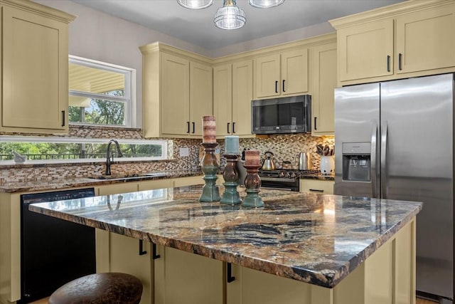 114 Deer Run, Moody, TX 76557 - kitchen with black appliances, cream cabinetry, dark stone countertops, backsplash, and a kitchen island