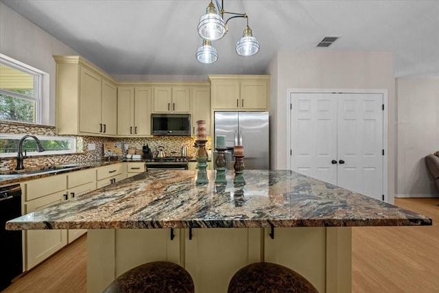 114 Deer Run, Moody, TX 76557 - kitchen featuring cream cabinets, appliances with stainless steel finishes, light wood-style flooring, tasteful backsplash, and dark stone countertops