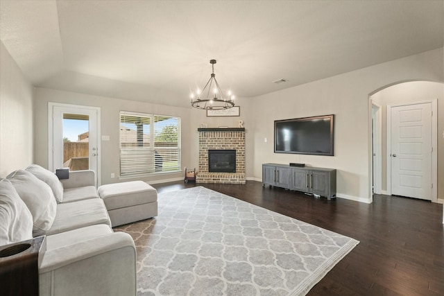 2205 Perrymead Dr, Forney, TX 75126 - living room featuring dark wood finished floors, a chandelier, arched walkways, a fireplace, and lofted ceiling