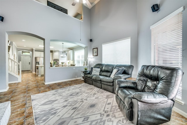 11543 Las Polamas Dr, Frisco, TX 75033 - living area with arched walkways, ceiling fan, baseboards, crown molding, and a towering ceiling