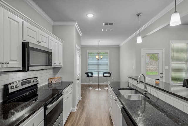 2939 Meadow Brook Trl, Tyler, TX 75701 - kitchen featuring stainless steel appliances, a sink, white cabinets, light wood finished floors, and decorative backsplash
