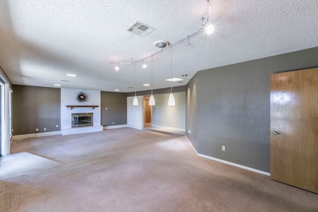 1604 Oak Hollow Dr, Woodway, TX 76712 - unfurnished living room with carpet, a textured ceiling, baseboards, track lighting, and a glass covered fireplace