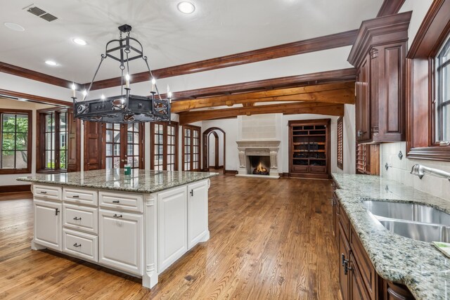 44 Armstrong Dr, Frisco, TX 75034 - kitchen featuring a chandelier, light wood-style floors, a center island, white cabinetry, and crown molding
