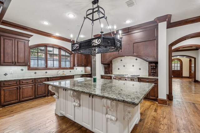 44 Armstrong Dr, Frisco, TX 75034 - kitchen featuring crown molding, a center island, decorative backsplash, arched walkways, and a sink