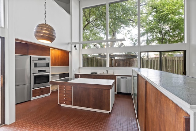 1703 E Barbara St, Tyler, TX 75701 - kitchen with appliances with stainless steel finishes, brown cabinetry, a sink, a kitchen island, and plenty of natural light