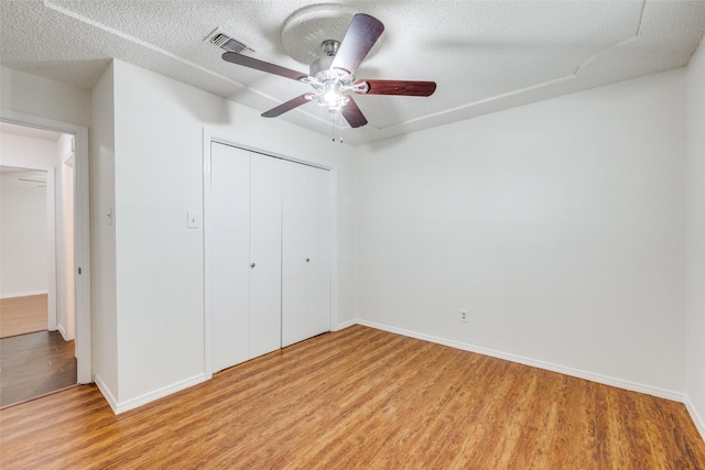 2505 Blue Quail Dr, Arlington, TX 76017 - unfurnished bedroom with light wood-type flooring, a closet, baseboards, a ceiling fan, and a textured ceiling