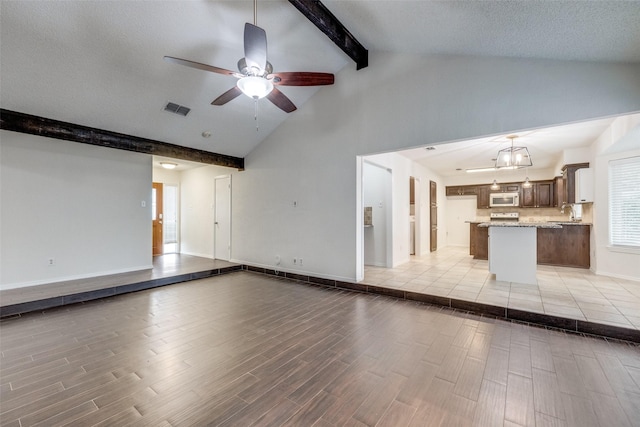 2505 Blue Quail Dr, Arlington, TX 76017 - unfurnished living room with beamed ceiling, a ceiling fan, high vaulted ceiling, light wood-style floors, and baseboards