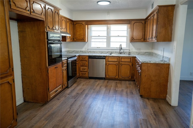 2206 Culbertson, Paris, TX 75460 - kitchen featuring appliances with stainless steel finishes, a sink, brown cabinetry, dark wood finished floors, and a textured ceiling