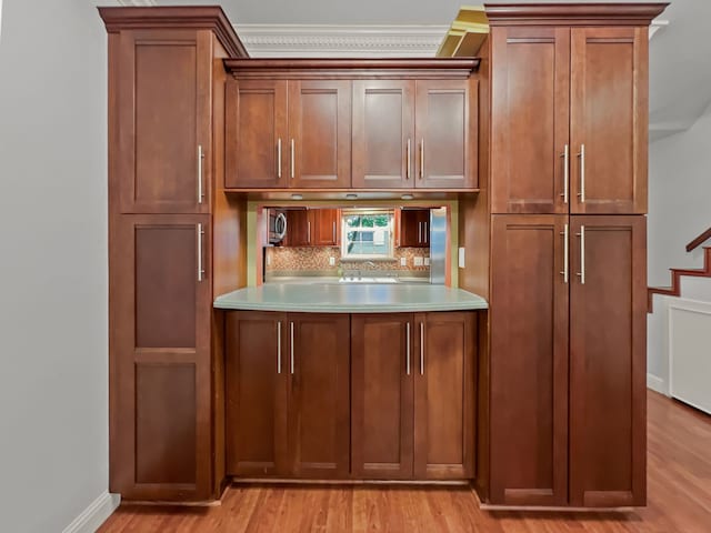 2727 Shelby Ave Unit X, Dallas, TX 75219 - kitchen featuring brown cabinetry, backsplash, light wood finished floors, light countertops, and a sink