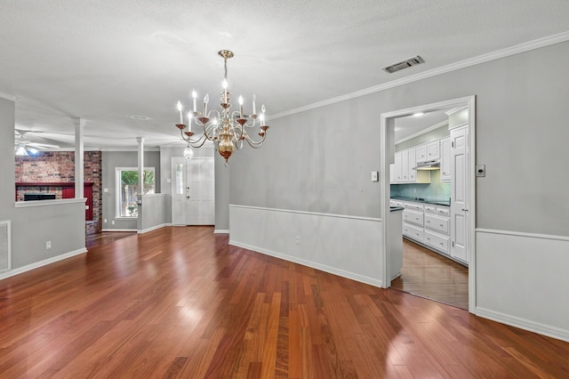 3410 Timbermill Rd, Waco, TX 76710 - unfurnished dining area featuring a chandelier, wood finished floors, a brick fireplace, ornamental molding, and baseboards