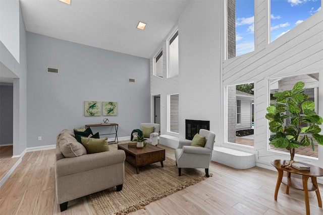 2100 Scarlet Oak Dr, Richardson, TX 75081 - living area with a high ceiling, light wood-type flooring, a glass covered fireplace, and baseboards