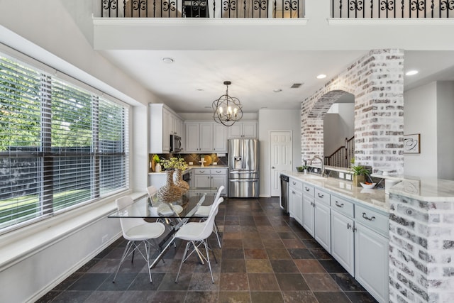 2398 April Sound Ln, Frisco, TX 75033 - kitchen featuring appliances with stainless steel finishes, white cabinetry, dark stone finish floors, a chandelier, and decorative light fixtures