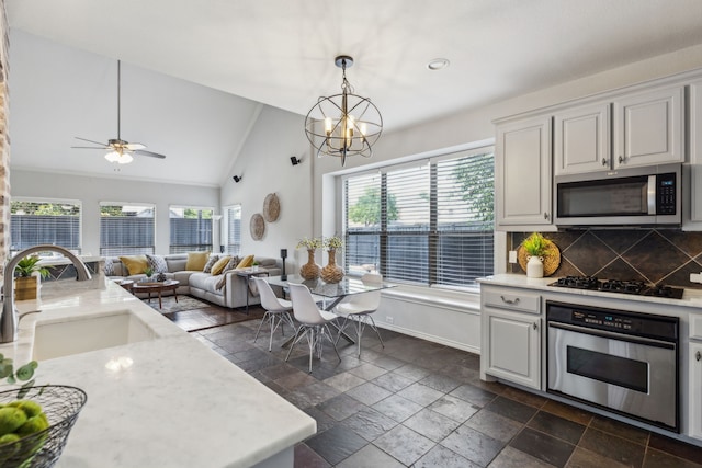 2398 April Sound Ln, Frisco, TX 75033 - kitchen featuring appliances with stainless steel finishes, a sink, vaulted ceiling, stone tile flooring, and decorative backsplash