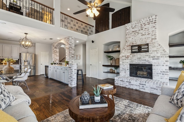 2398 April Sound Ln, Frisco, TX 75033 - living room featuring a towering ceiling, a ceiling fan, dark wood-type flooring, baseboards, and a brick fireplace