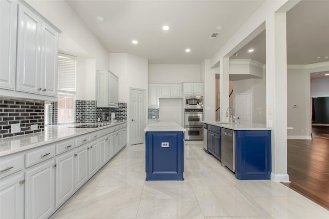 3700 Wagon Wheel Ct, Richardson, TX 75082 - kitchen with appliances with stainless steel finishes, tasteful backsplash, blue cabinetry, light countertops, and a center island