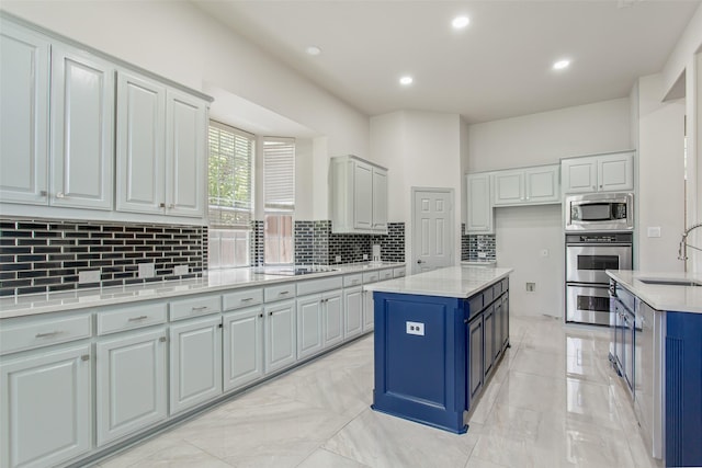 3700 Wagon Wheel Ct, Richardson, TX 75082 - kitchen with appliances with stainless steel finishes, blue cabinetry, backsplash, a center island, and light marble finish floors