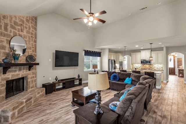 4323 Cherry Ln, Melissa, TX 75454 - living room with arched walkways, a ceiling fan, light wood-style floors, a fireplace, and high vaulted ceiling