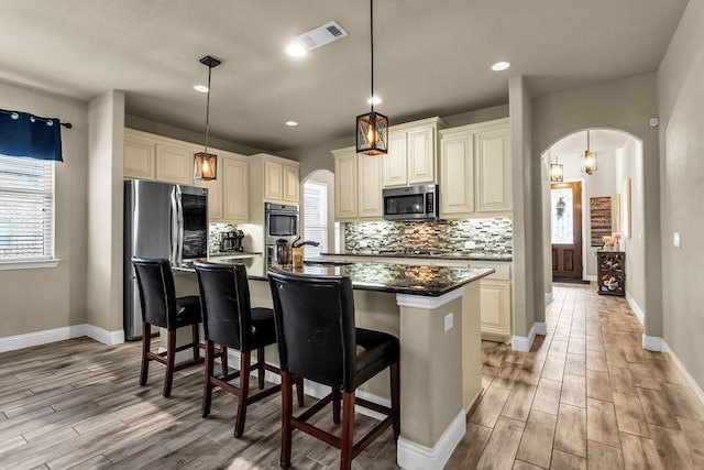 4323 Cherry Ln, Melissa, TX 75454 - kitchen featuring appliances with stainless steel finishes, arched walkways, light wood-style floors, tasteful backsplash, and recessed lighting
