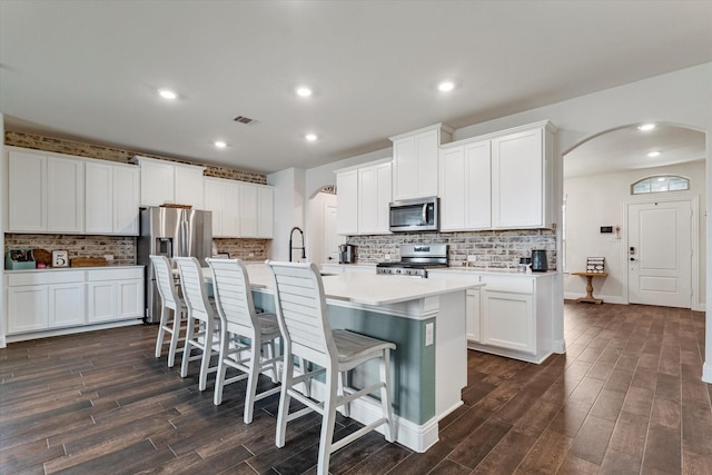 2709 Madera Canyon Rd, Aubrey, TX 76227 - kitchen with appliances with stainless steel finishes, arched walkways, dark wood-type flooring, a kitchen island with sink, and recessed lighting