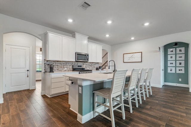 2709 Madera Canyon Rd, Aubrey, TX 76227 - kitchen featuring stainless steel appliances, arched walkways, dark wood finished floors, a kitchen island with sink, and recessed lighting
