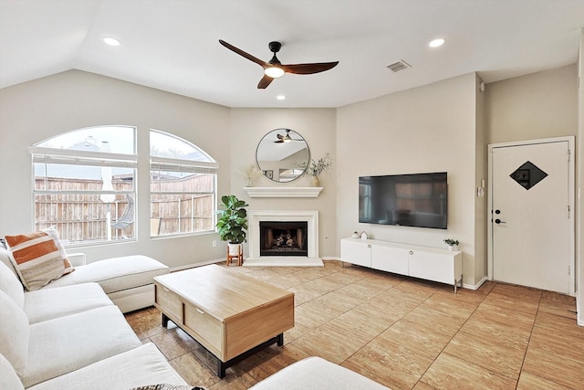 1689 Big Bend Dr, Lewisville, TX 75077 - living room with ceiling fan, vaulted ceiling, recessed lighting, a fireplace with raised hearth, and light tile patterned floors