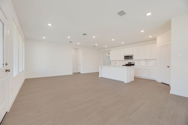 1301 Francesca Dr, Little Elm, TX 75068 - unfurnished living room featuring light wood-type flooring, recessed lighting, baseboards, and a sink