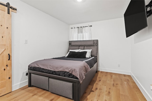3412 Regal, Mesquite, TX 75149 - bedroom featuring a barn door, wood finished floors, and baseboards