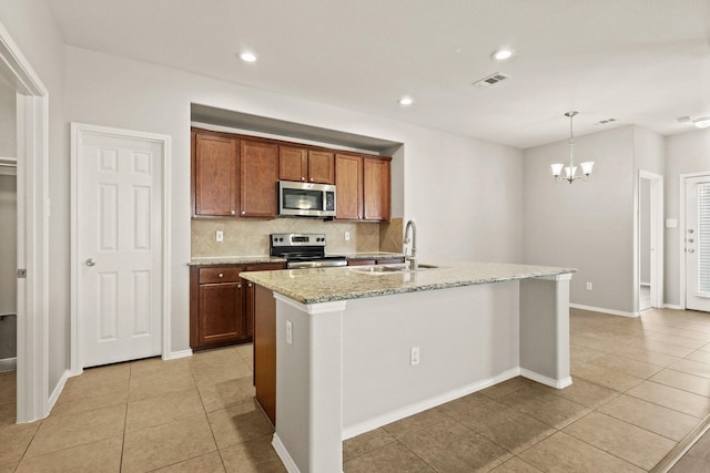 2004 Uvalde Dr, Forney, TX 75126 - kitchen featuring appliances with stainless steel finishes, a sink, light tile patterned floors, backsplash, and a center island with sink