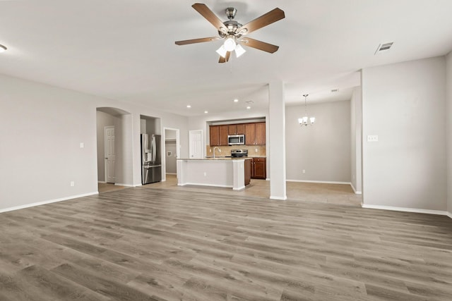 2004 Uvalde Dr, Forney, TX 75126 - unfurnished living room with arched walkways, baseboards, a sink, light wood-style floors, and recessed lighting
