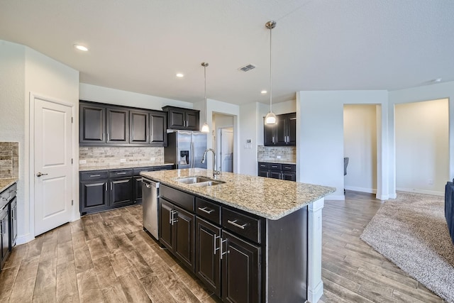 1217 Burlingame Dr, Cleburne, TX 76033 - kitchen featuring a sink, stainless steel appliances, decorative backsplash, light wood-style floors, and light stone countertops