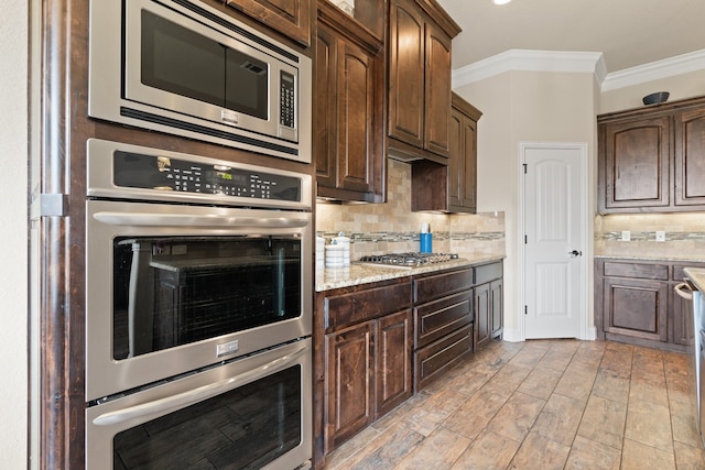 906 Joshua Ct, Granbury, TX 76048 - kitchen featuring appliances with stainless steel finishes, crown molding, dark brown cabinetry, and backsplash