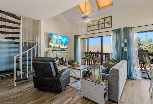 1006 Signal Ridge Pl, Rockwall, TX 75032 - living room featuring wood finished floors, a stone fireplace, stairs, and high vaulted ceiling