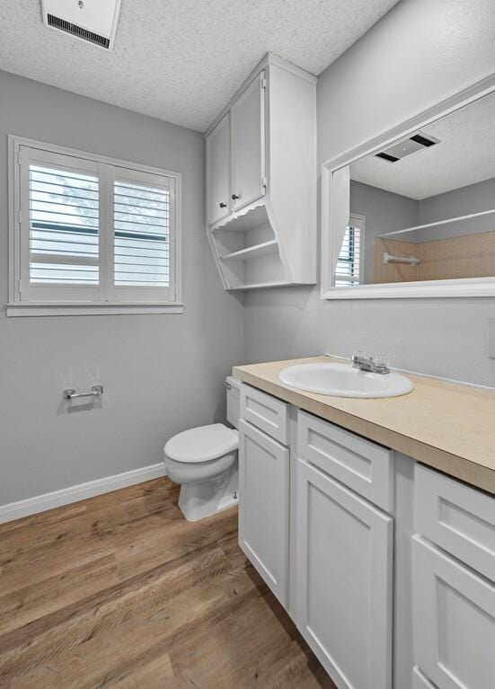 3732 N 24th St, Waco, TX 76708 - full bath featuring toilet, vanity, a textured ceiling, healthy amount of natural light, and wood finished floors