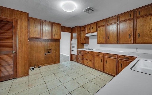 3732 N 24th St, Waco, TX 76708 - kitchen with brown cabinets, white appliances, light countertops, and under cabinet range hood