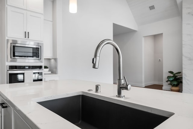 124 Craigmore Dr, Argyle, TX 76226 - kitchen featuring appliances with stainless steel finishes, a sink, light stone counters, white cabinetry, and vaulted ceiling