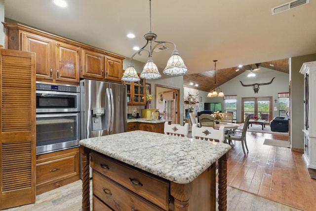 5925 Compass Way, Bluff Dale, TX 76433 - kitchen with stainless steel appliances, light stone countertops, lofted ceiling, brown cabinetry, and open floor plan