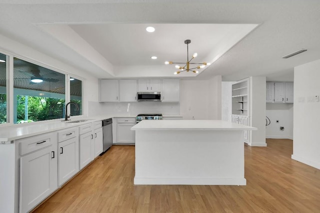 3008 Lindbergh Dr, Dallas, TX 75228 - kitchen featuring appliances with stainless steel finishes, a chandelier, light wood-style floors, a kitchen island, and light countertops