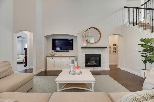 11578 Barcelona Ln, Frisco, TX 75035 - living room with arched walkways, a high ceiling, dark wood-type flooring, and baseboards