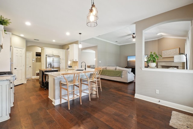 1300 Millers Creek Dr, Prosper, TX 75078 - kitchen with stainless steel refrigerator with ice dispenser, arched walkways, a ceiling fan, dark wood-style flooring, and ornamental molding
