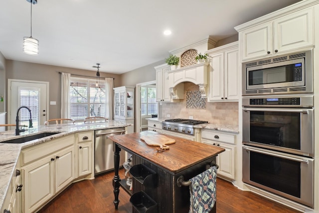 1300 Millers Creek Dr, Prosper, TX 75078 - kitchen with stainless steel appliances, a sink, light stone counters, hanging light fixtures, and recessed lighting