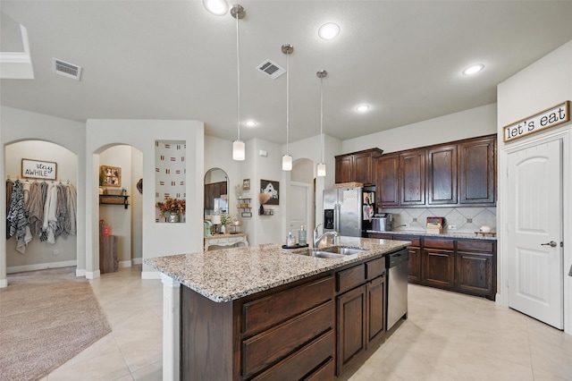 528 England St, Fate, TX 75189 - kitchen featuring appliances with stainless steel finishes, arched walkways, a sink, decorative backsplash, and light stone countertops