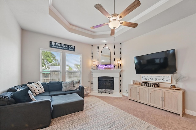 528 England St, Fate, TX 75189 - living room featuring ceiling fan, a raised ceiling, ornamental molding, a fireplace with raised hearth, and carpet