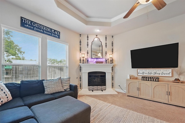 528 England St, Fate, TX 75189 - living room with a tray ceiling, light colored carpet, a ceiling fan, crown molding, and a fireplace with raised hearth