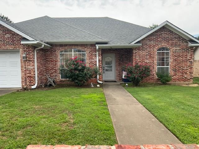 609 Mustang, Mount Vernon, TX 75487 - view of front of house featuring a shingled roof, brick siding, a front yard, and a garage