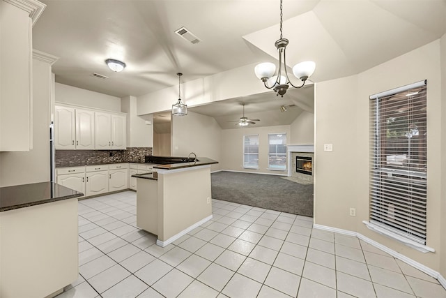 11 Enchanted Ct, Mansfield, TX 76063 - kitchen with vaulted ceiling, dark countertops, light tile patterned floors, white cabinetry, and a peninsula