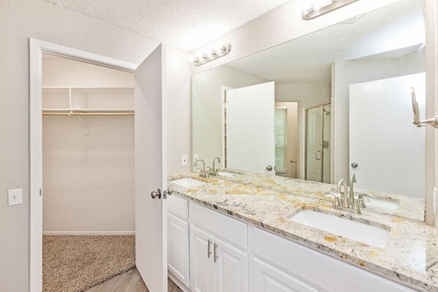 114 Juniper Dr, Arlington, TX 76018 - full bath featuring a stall shower, double vanity, a spacious closet, a textured ceiling, and wood finished floors